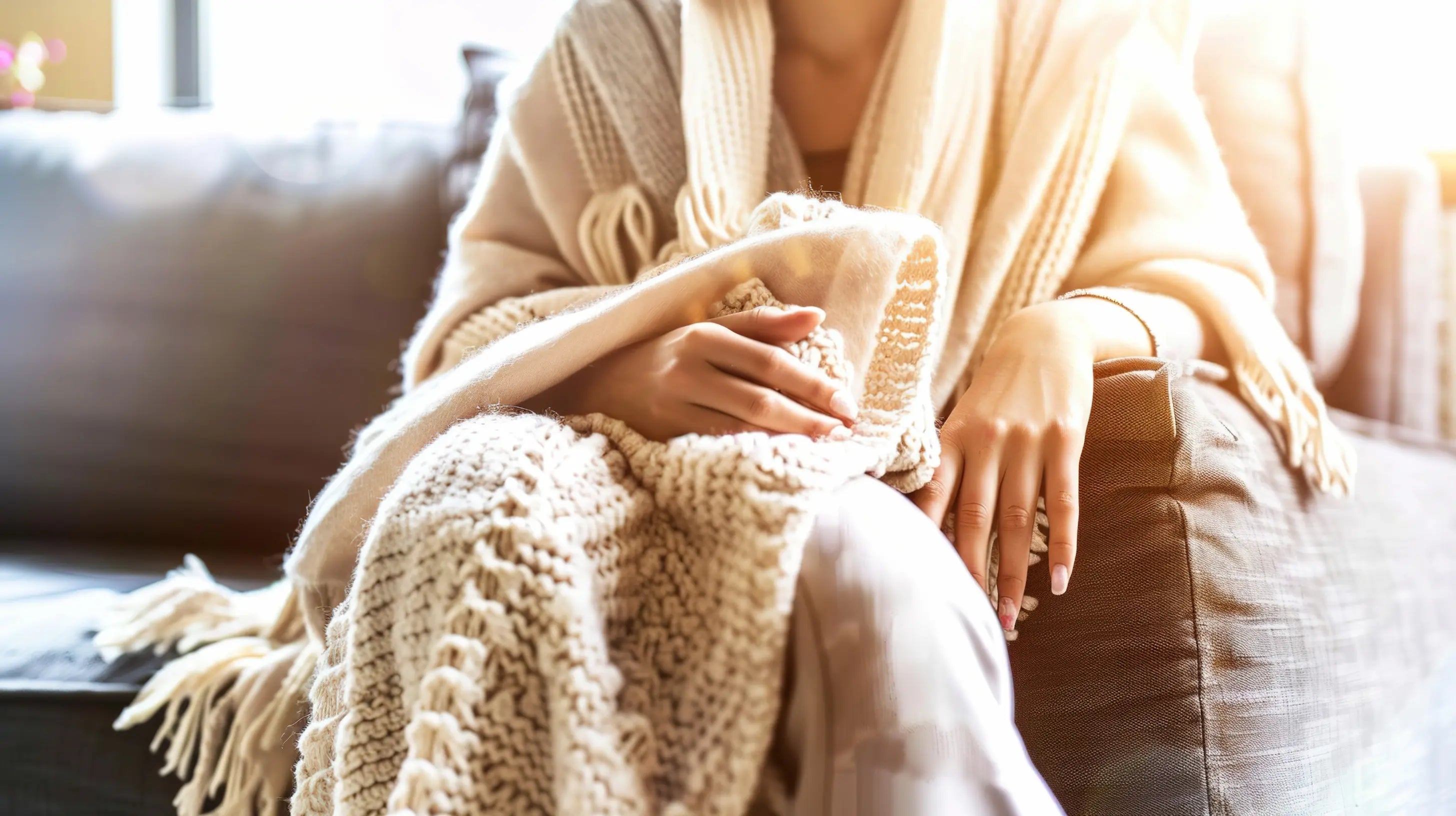Woman wrapped in a soft blanket resting on a couch during post-surgery recovery at home