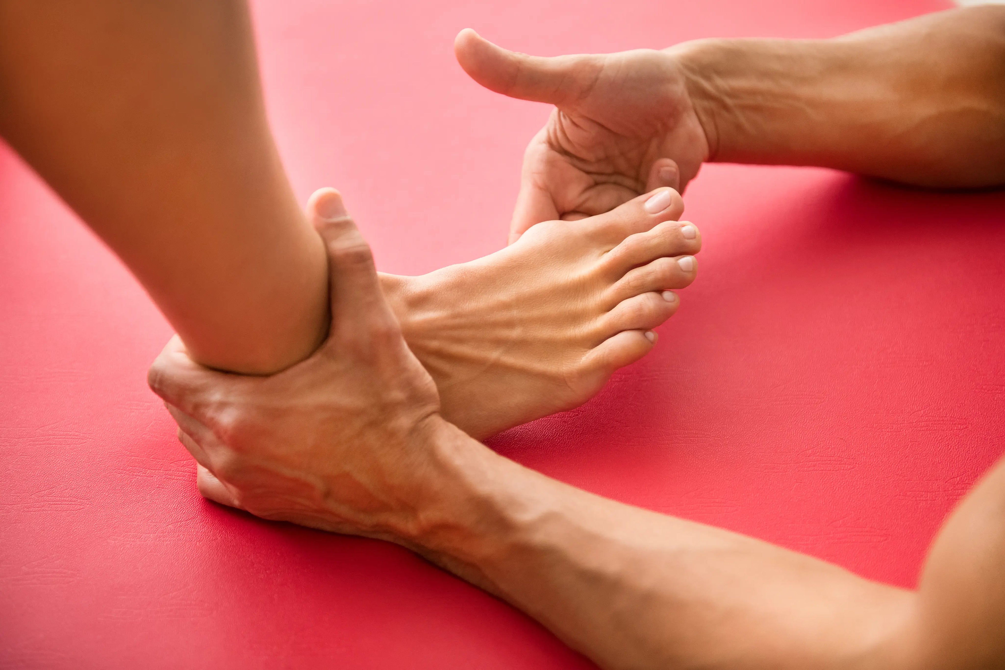 Hands performing foot stretch to relieve bunion pain and improve big toe alignment
