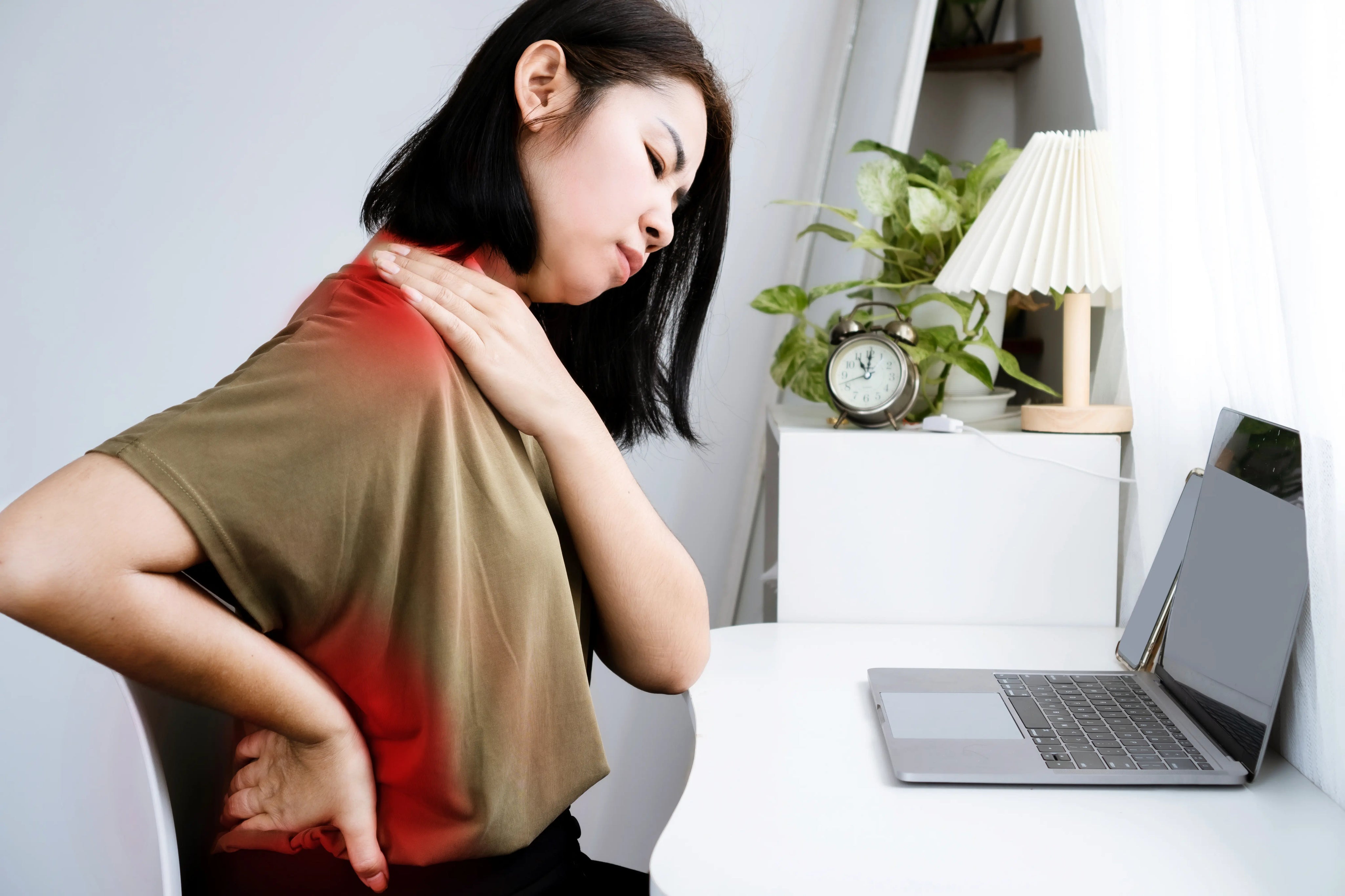 Person holding neck and lower back showing muscle stiffness and tension from prolonged sitting