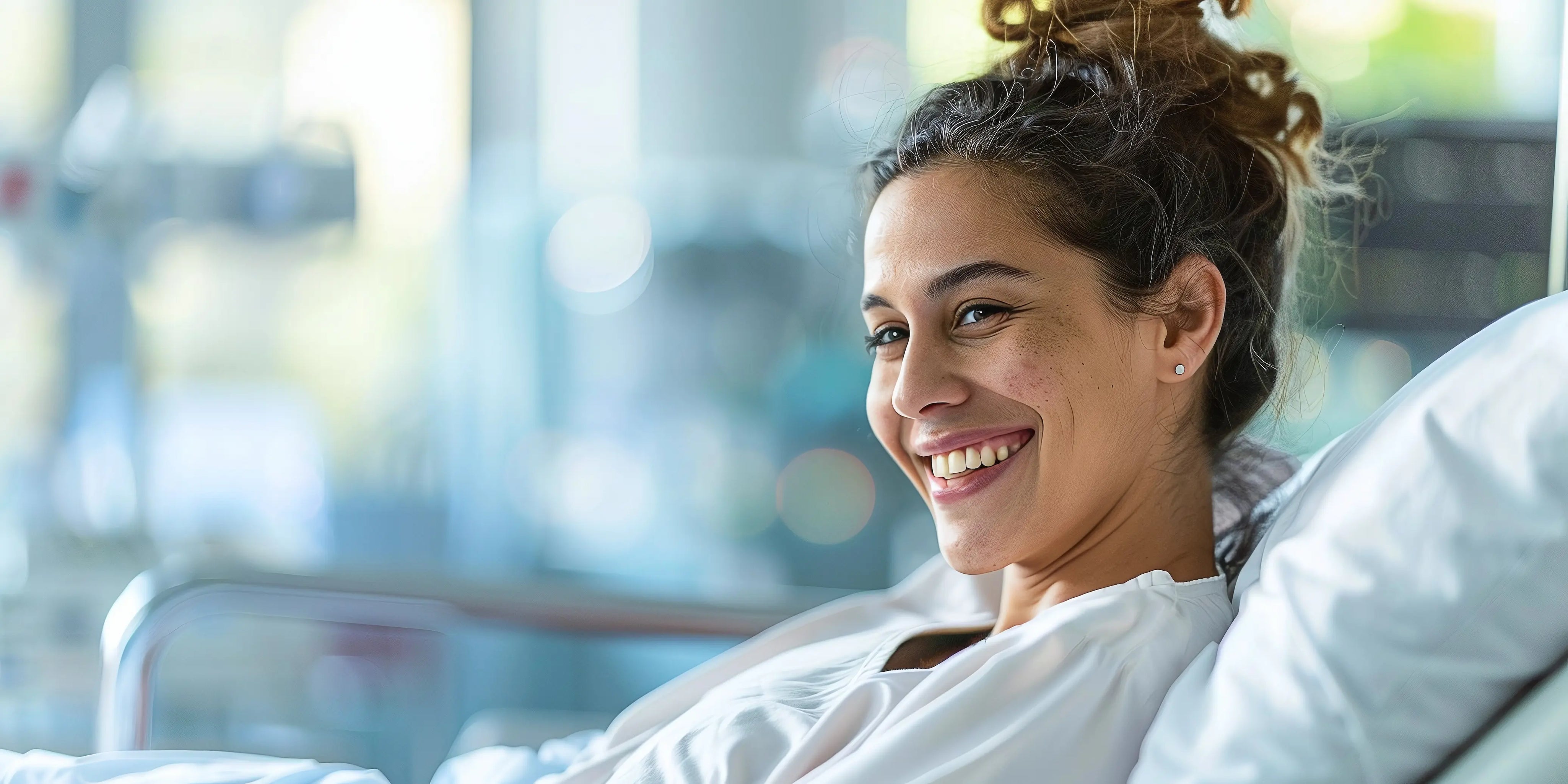 Smiling woman resting in a hospital bed during post-surgery recovery in a bright medical room