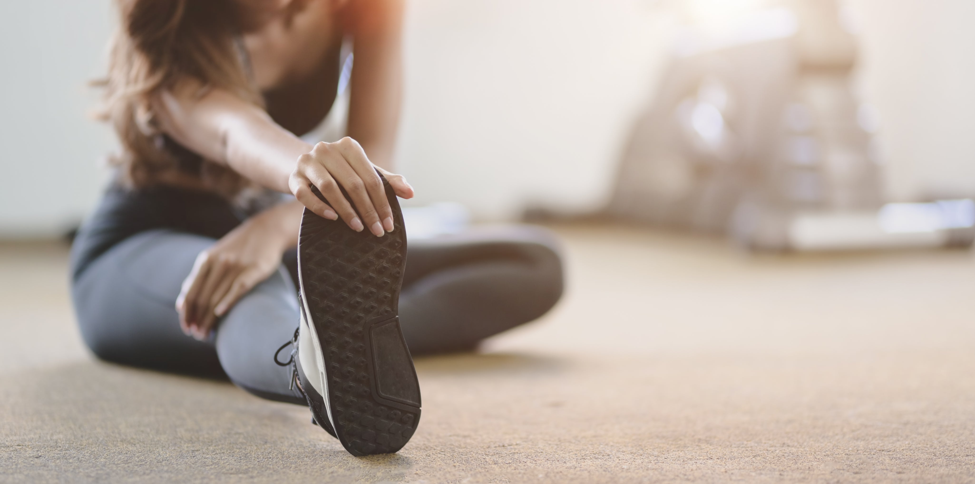 Person stretching a shoe indoors with a blurred background